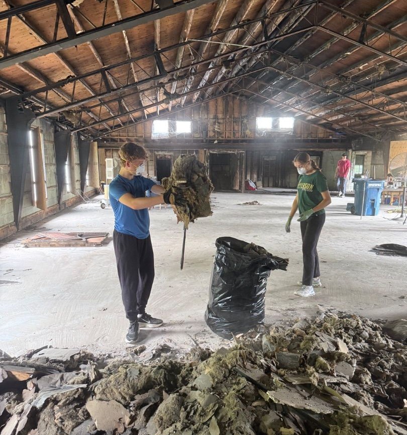Mission volunteers clearing debris from a large building