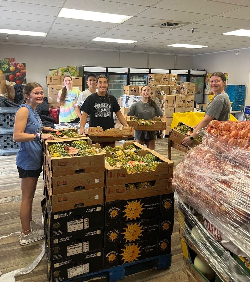 Mission volunteers helping organize fresh produce at a food pantry